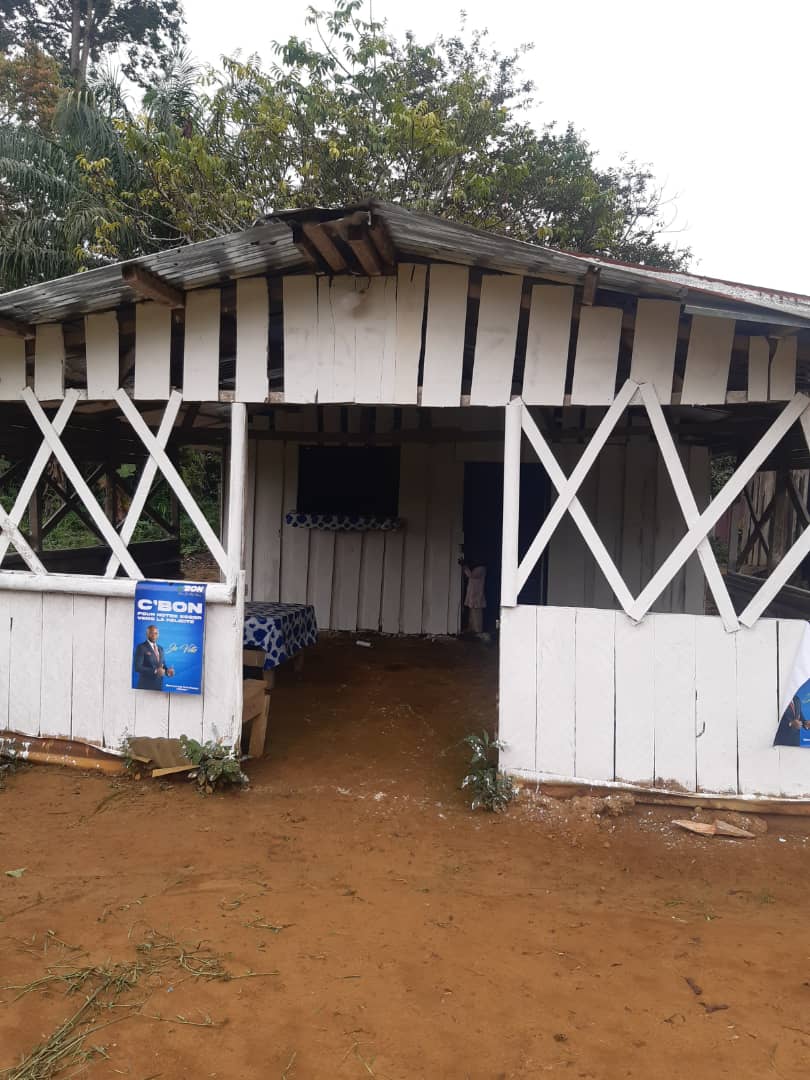 The village shop at Ntann, a white-painted wooden structure on red earth.